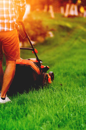 Portrait of man cutting the lawn, cutting the grass in backyard. Gardening and landscaping with professionalsの写真素材