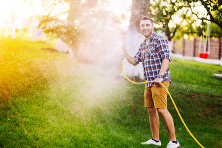 Gardening details - man playing with hose and watering the lawnの写真素材