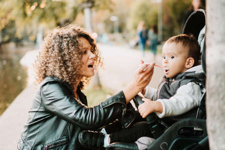 Portrait of mother feeding yogurt to 1 year old baby in stroller
の写真素材