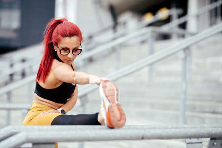 Active female runner stretching and relaxing muscles after hard workout. Fitness cross fit and...