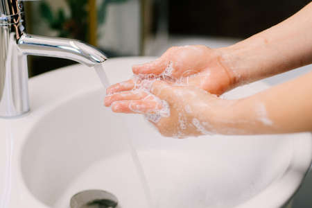 Close up of caucasian woman carefully washing hands with soap and sanitiser at home during worldwide coronavirus pandemicの写真素材