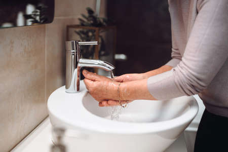 Woman carefully washing hands with soap and sanitiser at home during worldwide coronavirus pandemic