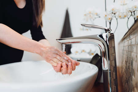 Caucasian woman carefully washing hands with soap and sanitiser in home bathroom