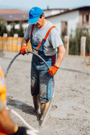 Construction worker working on building a house. Worker and concrete vibrator の写真素材