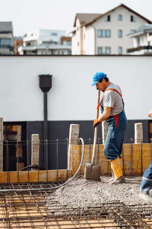 Mason building using a tools and leveling a first layer of fresh concrete floor at house, construction siteの写真素材