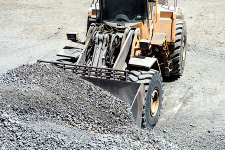 Close up of heavy duty large wheel loader loading gravel at work site. Construction site details, highway buildingの写真素材