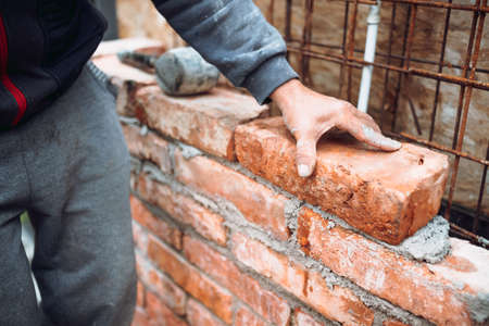 Industrial mason,  construction worker laying bricks and building walls on construction site. Detail...
