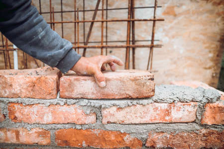 close up details of worker, bricklayer placing and adjusting bricks. Professional worker building...