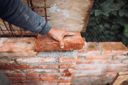 industrial bricklayer installing bricks on construction siteの写真素材