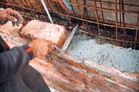 Industrial mason, bricklayer and construction worker using trowel and hands for building exterior...