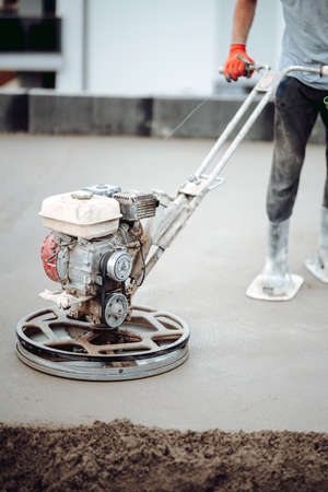 Helicopter concrete floor finishing on construction site. Construction worker finishing concrete screed with power trowel machineの写真素材