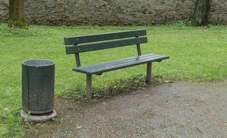 empty bench near a trash can in a parkの写真素材
