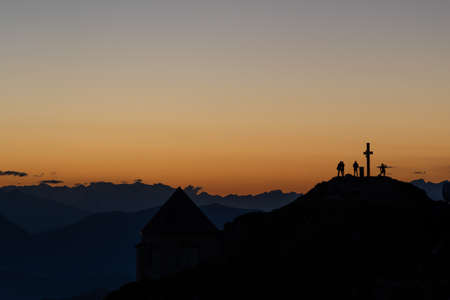 silhouette of hikers on a peak of a mountain topの写真素材