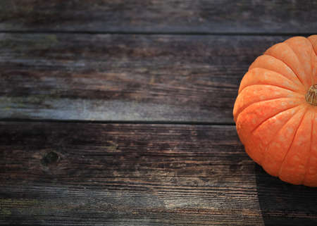 a half of a beautiful juicy pumpkin on a wooden table on dark backgroundの写真素材