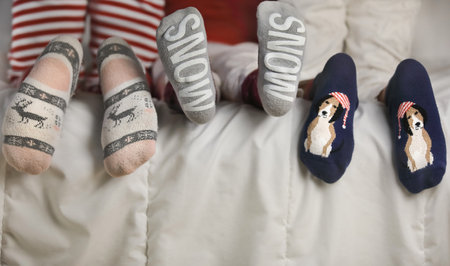 Feets wearing Christmas socks on a white blanket. Happy family at home.Christmas holidays conceptの写真素材
