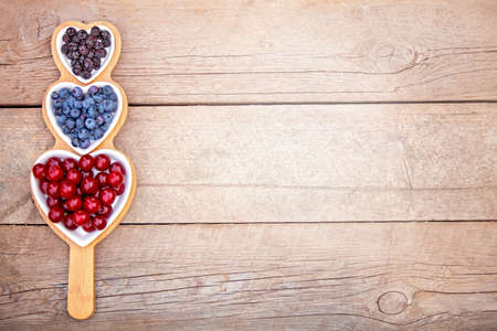 Portion wooden dish on light wooden background top view. Wooden partitioned dish divided into equal 3 sections. Compartmentals dish for food, dessert, fruit, berries and vegetables.の写真素材