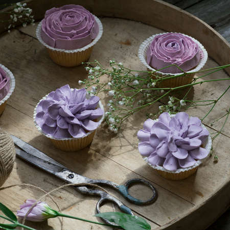 Cupcakes decorated with cream flowers on a wooden background. Close upの写真素材