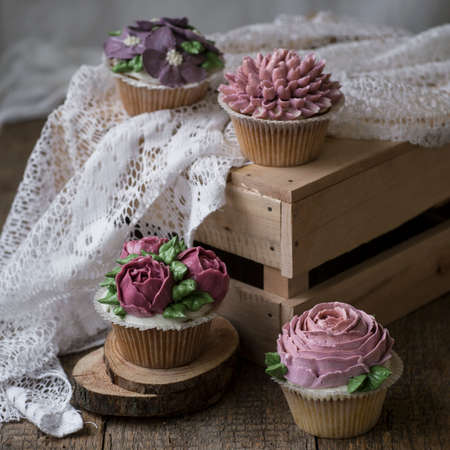 Cupcakes decorated with cream flowers: roses, peonies, chrysanthemums, poppies, scabiosa, napkinの写真素材
