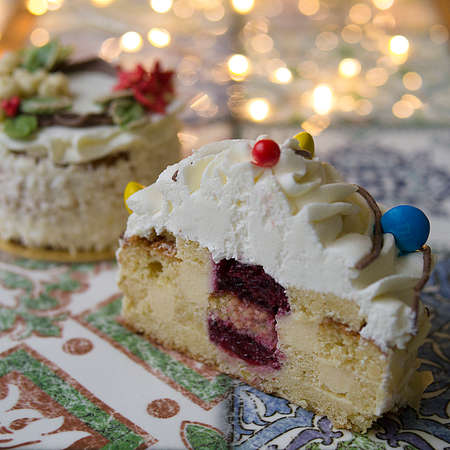 White New Year or Christmas cake decorated with cream poinsettia flowers, pine cones, cottons and spruce twigs on a colorful table. A birthday cake for those born in winter.Copy space, selective focusの写真素材