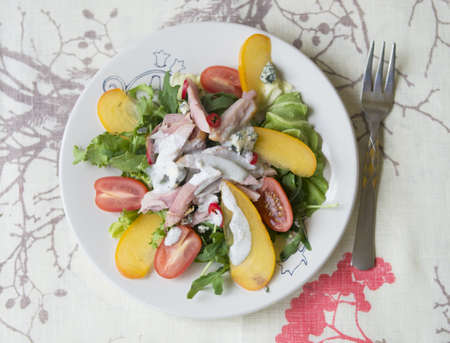 Salad with persimmon, smoked chicken, cherry tomatoes, Camembert cheese and blue cheese sauce. Festive dish . Christmas dinner. Selective focus, closeup, copy space, top view, from aboveの写真素材