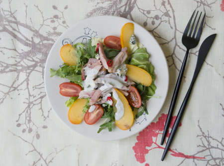 Salad with persimmon, smoked chicken, cherry tomatoes, Camembert cheese and blue cheese sauce. Festive dish . Christmas dinner. Selective focus, closeup, copy space, top view, from aboveの写真素材