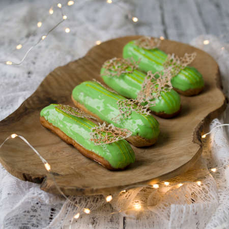 Eclairs with tangerine jelly, orange mousse and mascarpone cream decorated with green icing and gold...