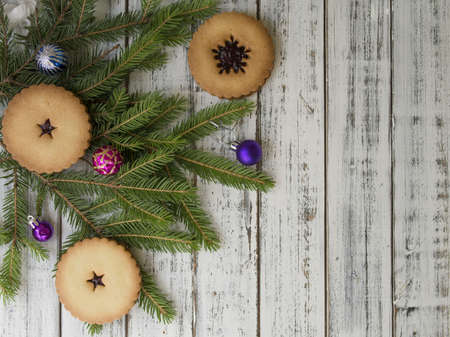 Christmas cookies with spices on wooden table with fir tree branches decorated with spruce balls. Festive New Years atmosphere. Christmas card. Selective focus, copy space, top viewの写真素材
