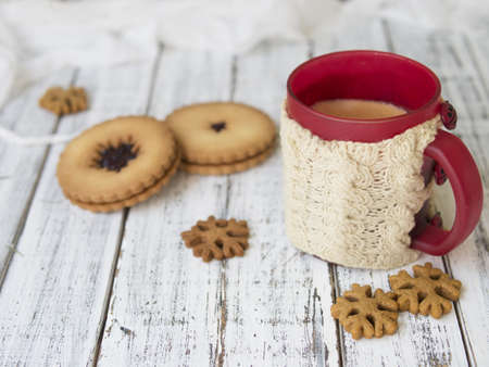 Winter morning, cups of coffee with knitted cup holders, gingerbread and vanilla cookies on a white wooden background.Cozy winter breakfast.Ideal for winter couple in love. Copy space, selective focusの写真素材