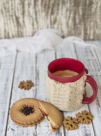 Winter morning, cups of coffee with knitted cup holders, gingerbread and vanilla cookies on a white wooden background.Cozy winter breakfast.Ideal for winter couple in love. Copy space, selective focusの写真素材