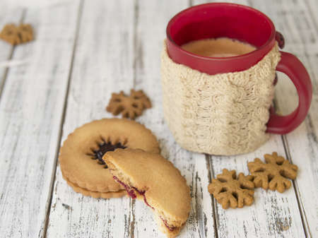 Winter morning, cups of coffee with knitted cup holders, gingerbread and vanilla cookies on a white wooden background.Cozy winter breakfast.Ideal for winter couple in love. Copy space, selective focusの写真素材