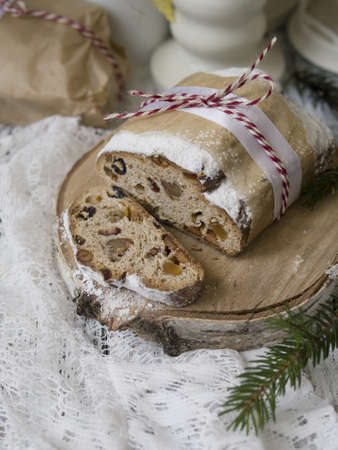 Dresden Christmas Stollen with raisins, dried apricots, dried cherries, nuts and candied fruits in sugar glaze on a festive background. Delicious festive Christmas dessert. Copy space, selective focusの写真素材