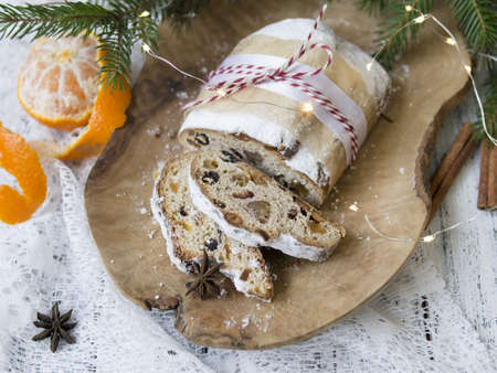 Traditional European Christmas pastry, fragrant home baked stollen, with spices and dried fruit. Sliced on wooden table with xmas tree branches and decorations, copy space, selective focusの写真素材