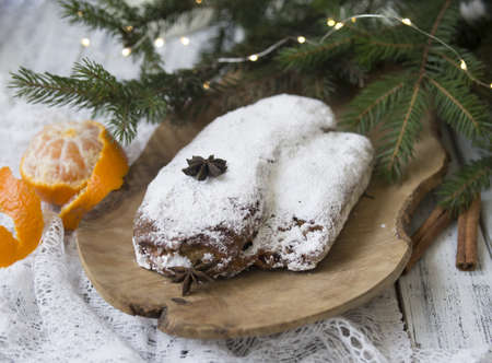 Christmas stollen on white background with spruce twigs and tangerines. Traditional Christmas festive pastry, dessert. Stollen for Christmas. Copy space, selective focus, top viewの写真素材