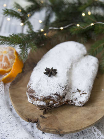 Christmas stollen on white background with spruce twigs and tangerines. Traditional Christmas festive pastry, dessert. Stollen for Christmas. Copy space, selective focus, top viewの写真素材