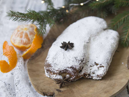 Christmas stollen on white background with spruce twigs and tangerines. Traditional Christmas festive pastry, dessert. Stollen for Christmas. Copy space, selective focus, top viewの写真素材