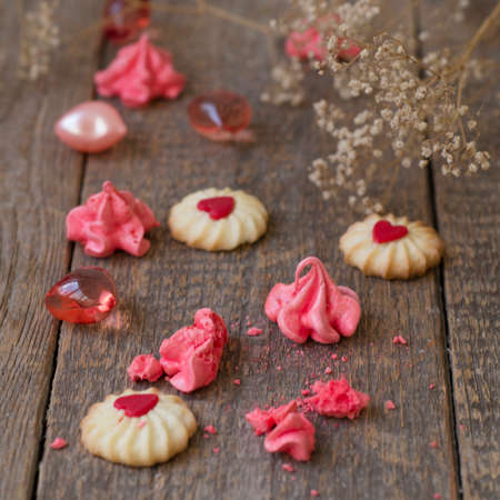 Pink meringue cookies in glass jar with heart on wooden table. Selective focus. Valentines Day...