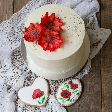 Beautiful White Poppy Seed cake with red pineapple poppy flowers. White cake on a wwooden background...