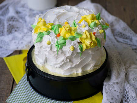 White cake decorated with cream spring flowers - daffodils - on wooden background with lace fabric. Vintage, retro. Gift for Women's Day, 8 March, Vaentine's Day. Close up, copy spaceの写真素材