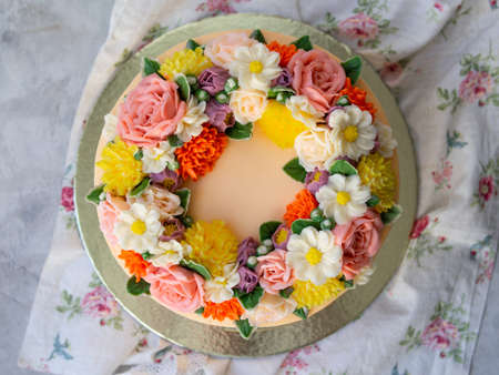 Yellow cream cake decorated with buttercream flowers - peonies, roses, chrysanthemums, carnations - on white wooden background. Card for March 8, Womens Day, Valentines Day. Copy space, top viewの写真素材