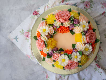 Yellow cream cake decorated with buttercream flowers - peonies, roses, chrysanthemums, carnations - on white wooden background. Card for March 8, Womens Day, Valentines Day. Copy space, top viewの写真素材