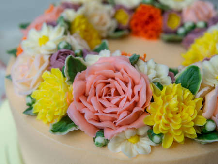 Yellow cream cake decorated with buttercream flowers - peonies, roses, chrysanthemums, carnations - on white wooden background. Card for March 8, Womens Day, Valentines Day. Close up, selective focusの写真素材