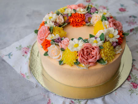Yellow cream cake decorated with buttercream flowers - peonies, roses, chrysanthemums, carnations - on white wooden background. Card for March 8, Womens Day, Valentines Day. Copy space,close upの写真素材