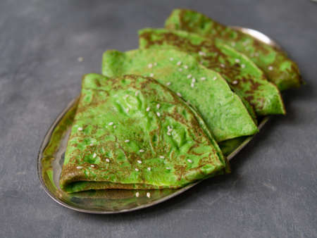 Green mint crepes on metal plate on gray background. Close up, selective focus. Gourmet breakfast. Maslenitsa. Russian thin crepesの写真素材