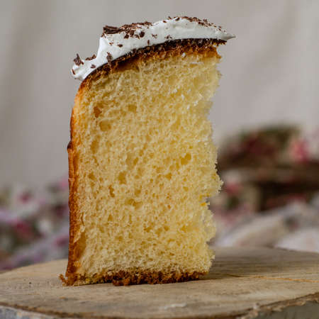 Slice of easter orthodox sweet bread, kulich on wooden background with floral fabric. Retro style. Breakfast. Close up, selective focus, copy spaceの写真素材