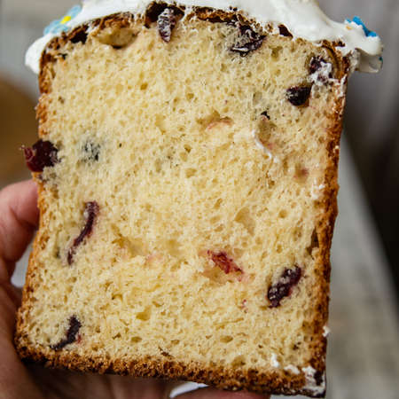 Half-cut homemade sweet easter bread in the hands of a baker's woman. Slice of easter orthodox sweet bread, kulich. Beautiful lace crumbs rolls. Close up, selective focus, copy spaceの写真素材