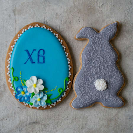 Happy family holiday, gingerbread easter cookies in form of rabbit and egg. Festive cookies on gray background. Selective focus, close up, copy space.の写真素材