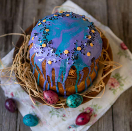 Traditionally baked orthodox easter cakes with glace icing and bright little eggs on wooden...