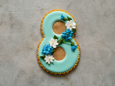 Cookie covered with blue glaze made in a form of number eight with flowers - cornflowers and daisies...