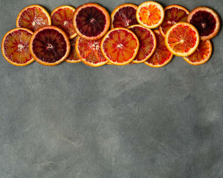 Blood juicy Sicilian orange slices on gray background. Sliced blood orange texture. Citrus background. Copy space, selective focus, top view. Minimalism style.の写真素材
