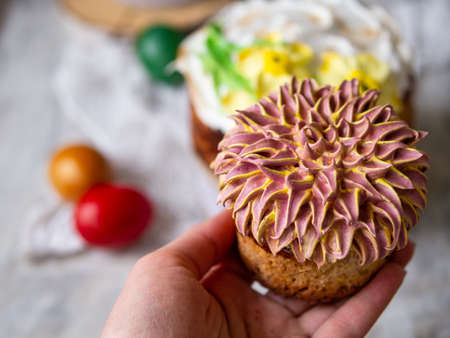 Easter cake kulich. Traditional Easter sweet bread decorated meringue, chrysanthemum in hand. Copy...